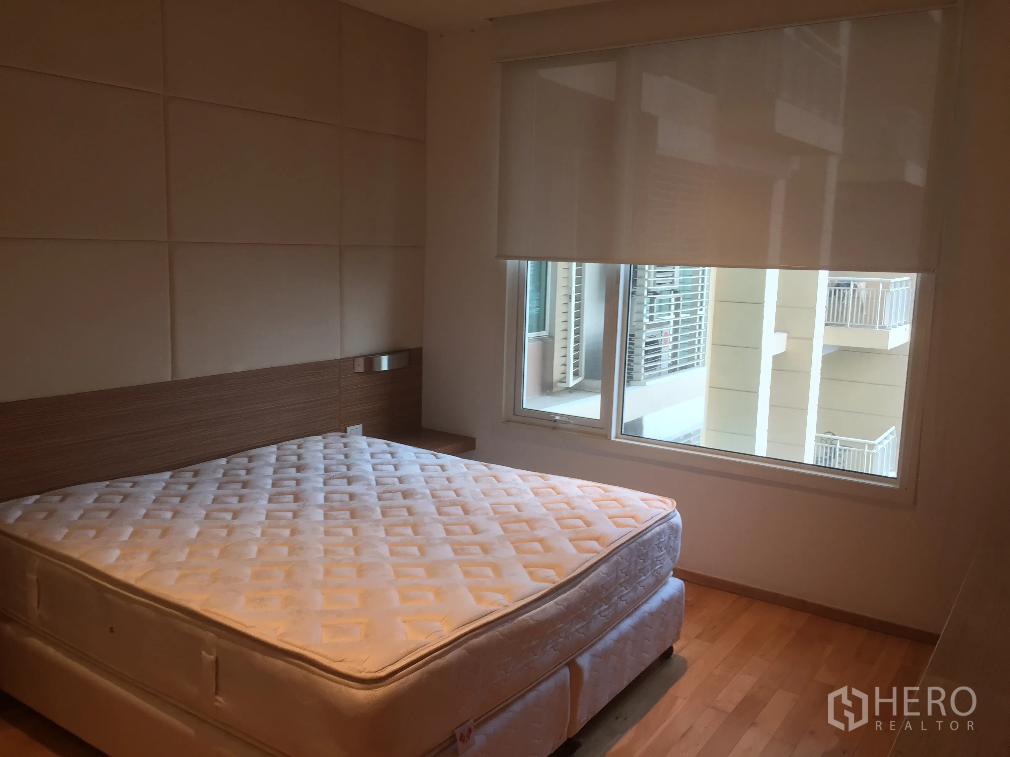Condominium for rent in Sathon, Bangkok - Cozy bedroom with large window, roller blind, wood flooring and a queen mattress.