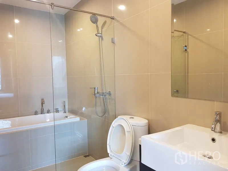 คอนโด ให้เช่าในRatchathewi, Bangkok - ห้องน้ำสมัยใหม่มีตู้กระจกอาบน้ำ อ่างอาบน้ำ อ่างล้างหน้าเหลี่ยม และกระเบื้องโทนอ่อน