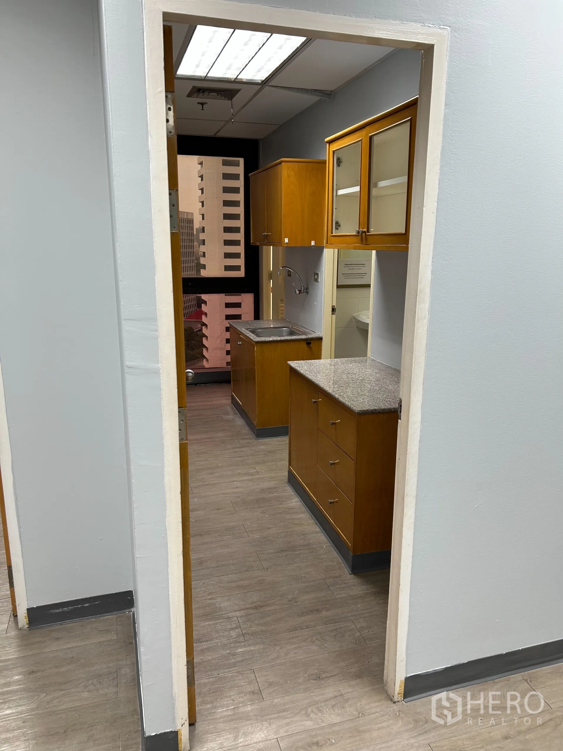 办公空间 出租在Khlong Toei, Bangkok - 紧凑茶水间，木质柜体、操作台、不锈钢水槽与外窗。