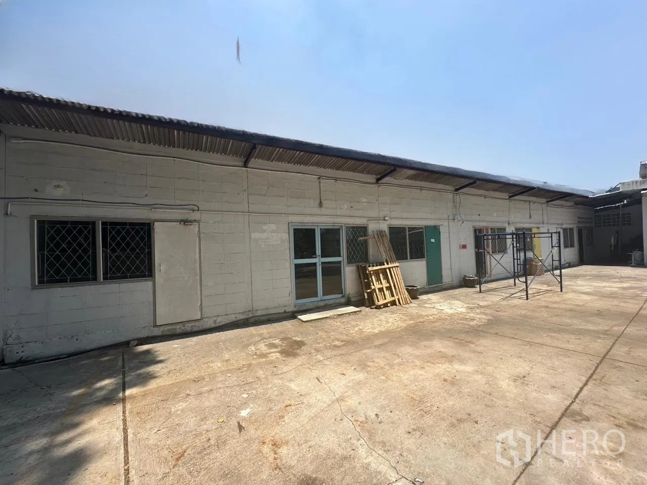 Warehouse for rent in Din Daeng, Bangkok - Rear service building with paved yard and metal roofing.
