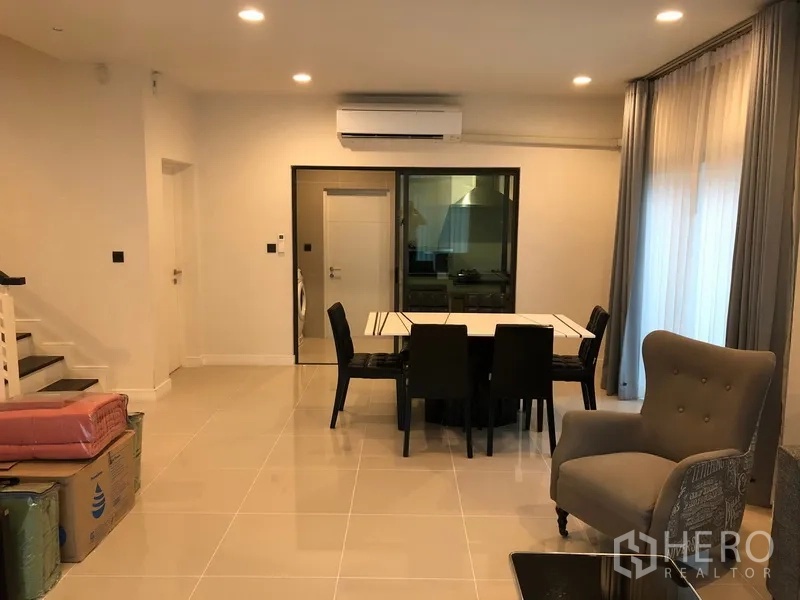 Detached House for rent or sale in Bang Kapi, Bangkok - Open dining area with six-seat table, stairway and sliding door leading to the closed kitchen.