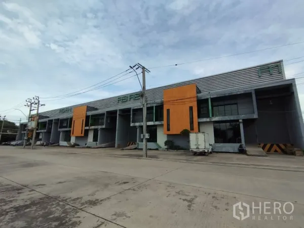 工厂 出租在Samut Prakan - 现代联排仓库与工厂外观，橙色立面点缀，装卸平台与宽阔道路。