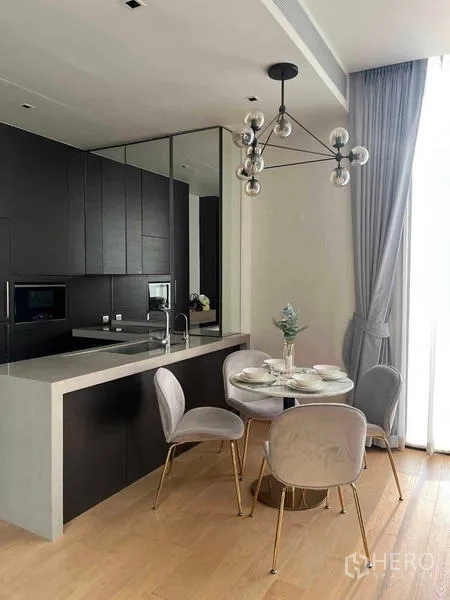 Condominium for rent - Sleek open kitchen with dark cabinetry, built-in appliances, breakfast counter, and adjacent dining area filled with natural light.