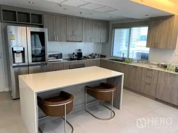 Condominium for rent in Sathon, Bangkok - Fully fitted L-shaped kitchen with wood cabinets, island breakfast bar and double-door fridge.