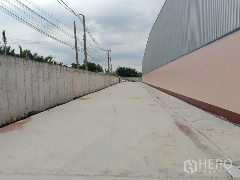 Factory for rent in Ban Phaeo, Samut Sakhon - Side driveway along the factory’s perimeter wall for smooth truck circulation and loading access.
