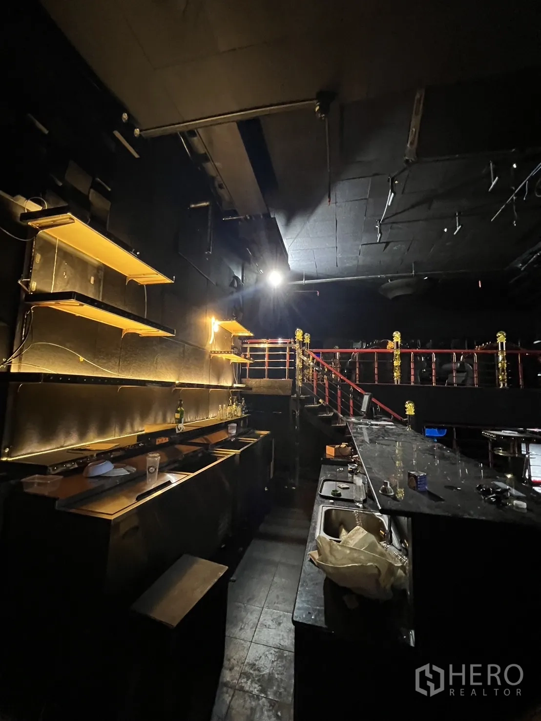 零售空间 出租 - 黑色石材长吧台特写，带背光架与水槽。