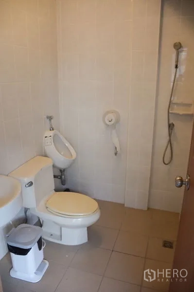 联排别墅 出租在Watthana, Bangkok - 瓷砖卫生间，坐便器、小便斗与壁挂花洒。