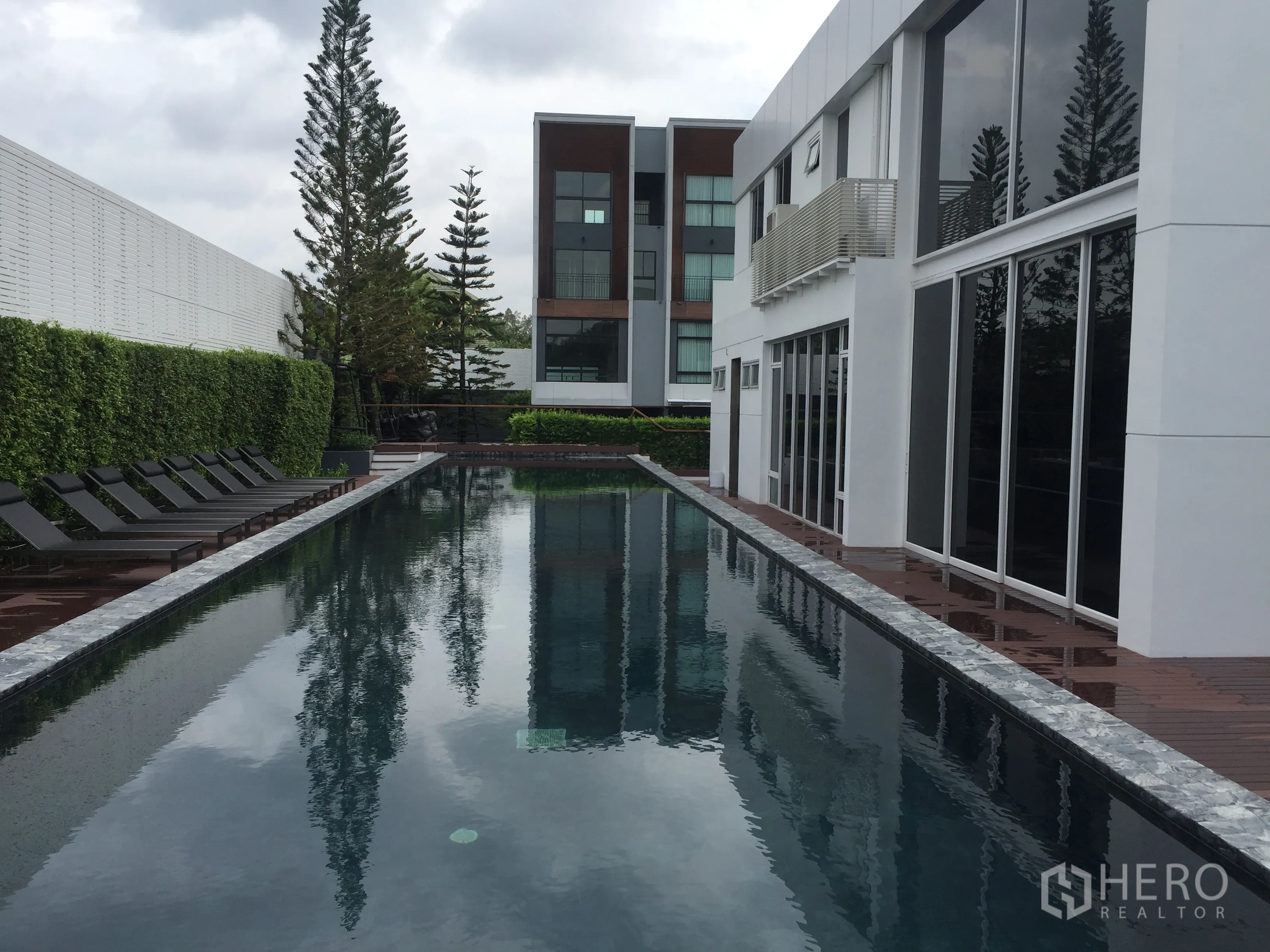 Townhouse for rent in Suan Luang, Bangkok - Long outdoor swimming pool with sun loungers and a modern clubhouse.