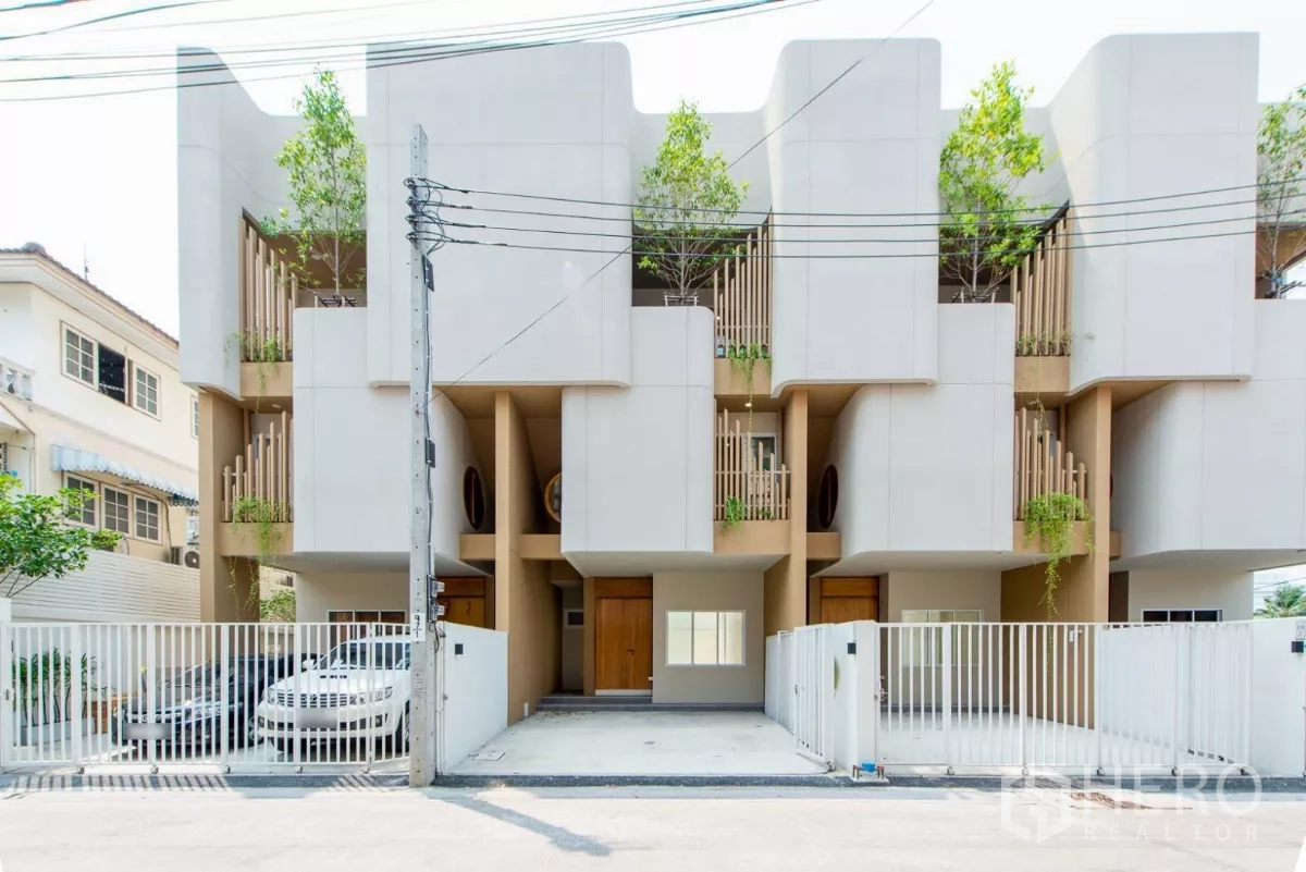 联排别墅 出售在Lat Phrao, Bangkok - 现代三层联排别墅立面，私家车位与绿植阳台