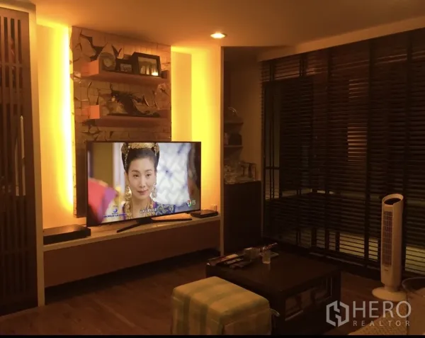 Condominium for sale in Yan Nawa, Bangkok - Cozy media corner with backlit TV wall, shelving and dark window blinds.