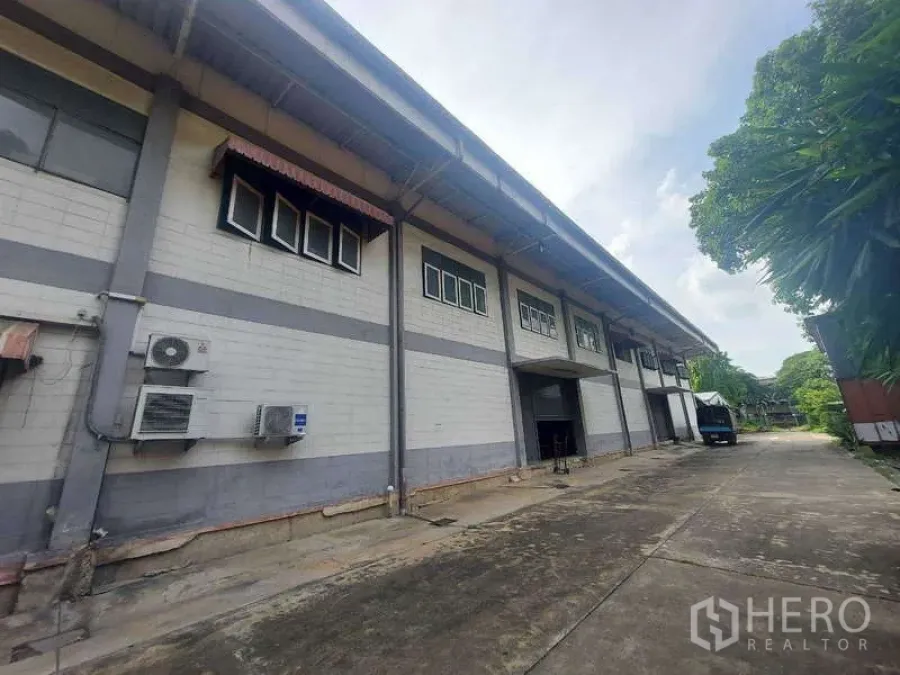 Warehouse for rent in Min Buri, Bangkok - Warehouse exterior showing loading bay doors, truck access lane and utilities.