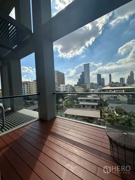 Condominium for rent or sale in Sathon, Bangkok - Private balcony with wood decking and glass railing overlooking the city skyline.