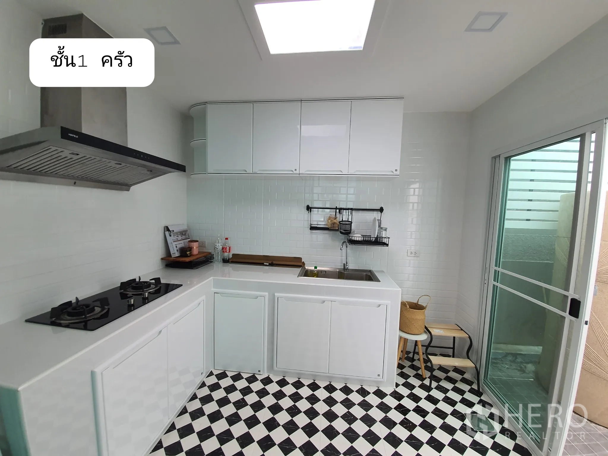 Home Office for rent or sale in Prawet, Bangkok - Modern white kitchen with gas hob, hood, built-in cabinets and black-and-white checkered floor.