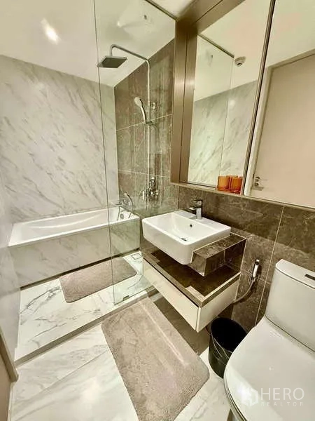 Condominium for rent - Contemporary bathroom with glass shower, bathtub, large mirror and marble-style tiles.