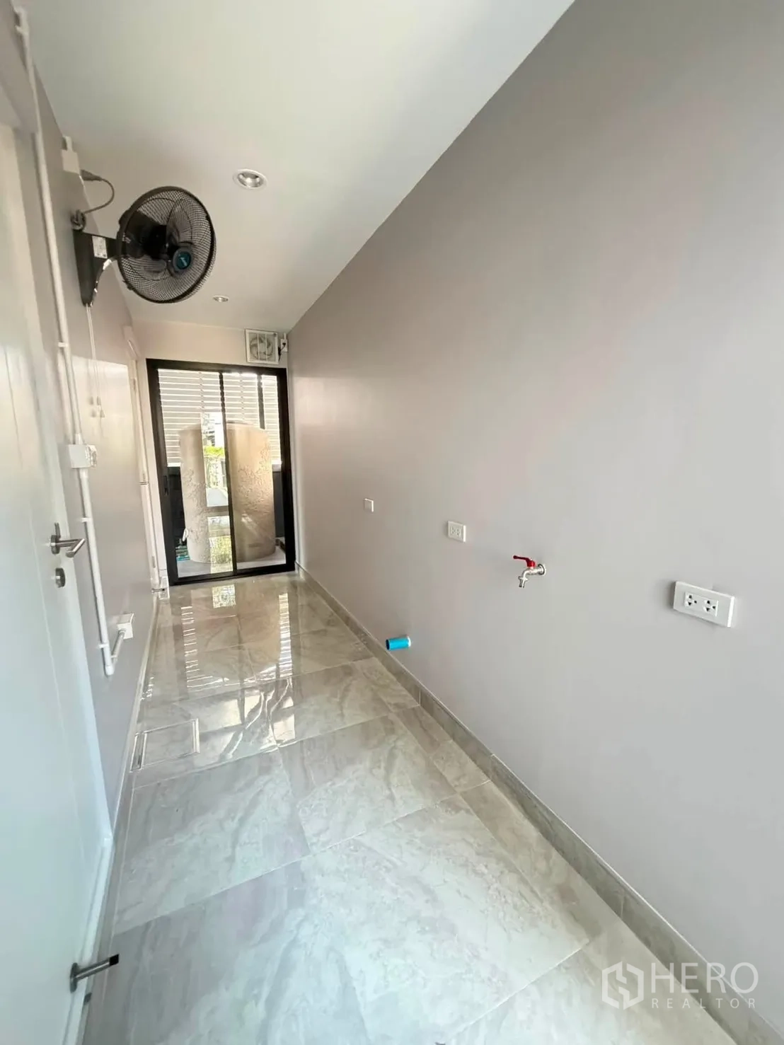 Detached House for rent or sale in Prawet, Bangkok - Narrow service corridor with glossy tiles, wall fan, and sink tap.