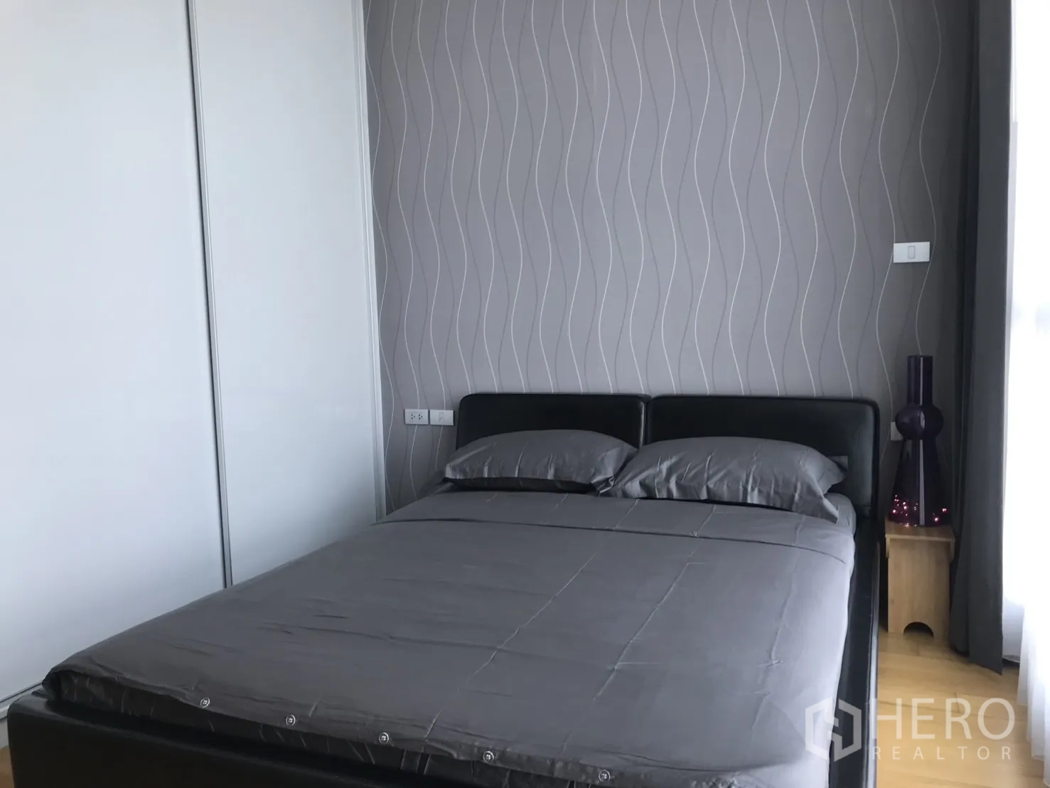 Condominium for rent in Watthana, Bangkok - Second bedroom with gray bedding and wavy-patterned wallpaper.