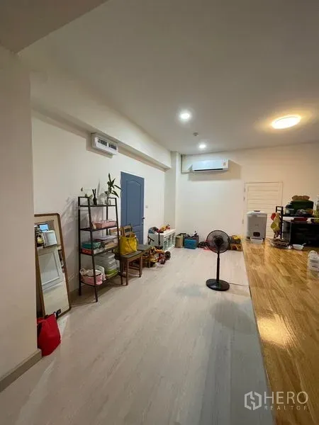 Condominium for sale in Sathon, Bangkok - Long open-plan space with air-conditioning, shelving and pale wood flooring.