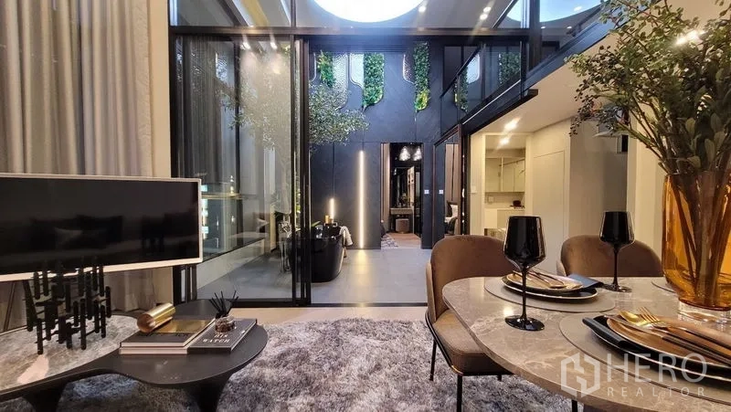 Detached House for sale in Watthana, Bangkok - Dining table and TV facing the internal courtyard with vertical greenery and accent lighting.