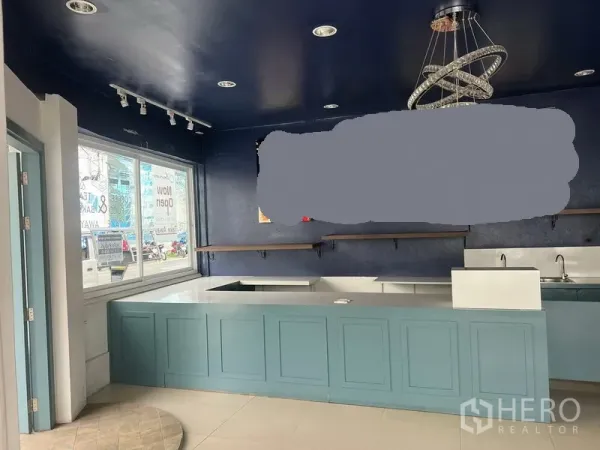 零售空间 出租在Watthana, Bangkok - 内置服务吧台与蓝色柜体，水槽、搁架和现代吊灯。