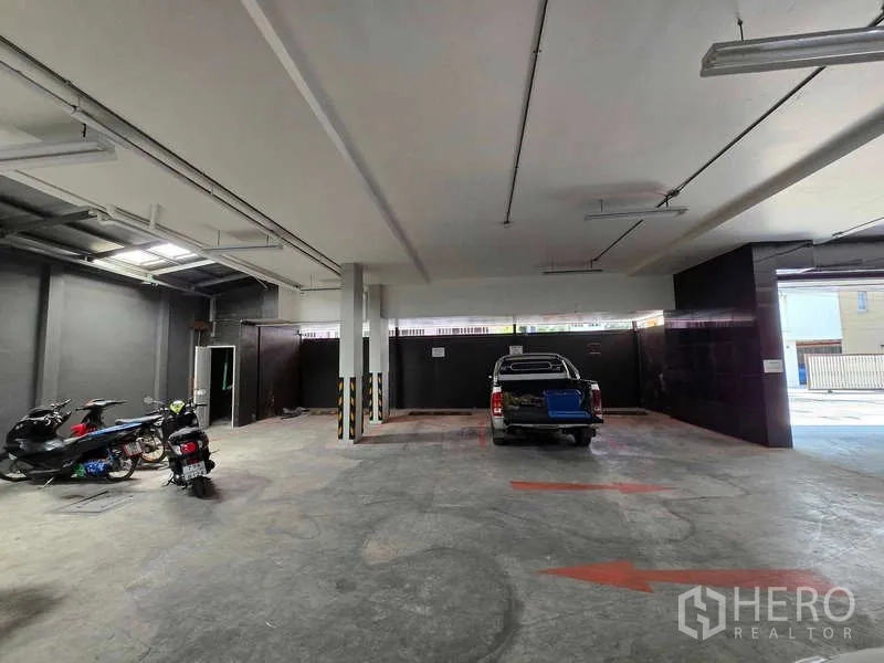 พื้นที่ขายปลีก ให้เช่าในKhlong Toei, Bangkok - พื้นที่จอดรถชั้นล่างในร่ม พื้นคอนกรีต ไฟเพดาน พร้อมมอเตอร์ไซค์และรถกระบะ