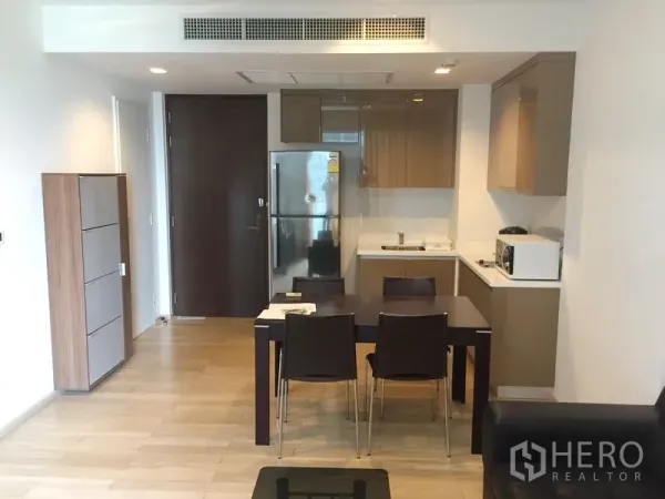 คอนโด ให้เช่าในKhlong Toei, Bangkok - ครัวและส่วนทานอาหารแบบเปิด พร้อมตู้บิลท์อิน ตู้เย็นสแตนเลส และโต๊ะอาหาร 4 ที่นั่ง ในคอนโดสไตล์โมเดิร์น