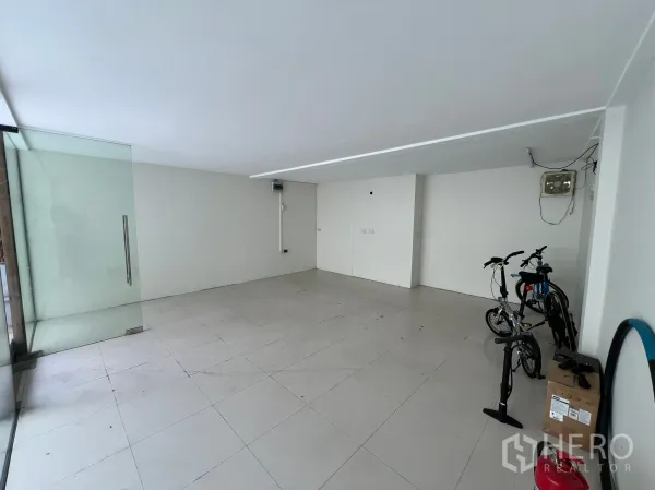 零售空间 出租在Watthana, Bangkok - 开放式店铺空间，整面玻璃入口，侧边可见自行车。