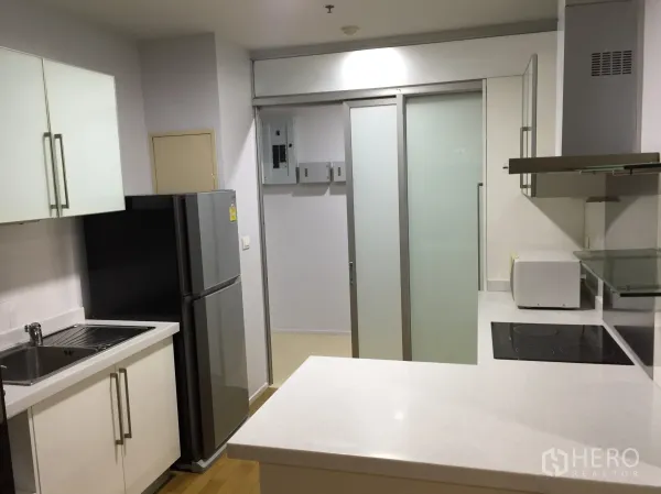 คอนโด ให้เช่าในWatthana, Bangkok - ครัวบิลต์อินโทนขาว เตาไฟฟ้า เครื่องดูดควัน ตู้เย็น และประตูกระจกฝ้าแบบบานเลื่อน