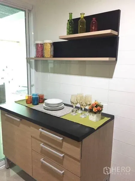 คอนโด ขายในWatthana, Bangkok - แพนทรีขนาดกะทัดรัดพร้อมตู้ไม้ ท็อปสีดำ ชั้นลอย และแก้วไวน์ข้างประตูกระจกบานเลื่อน