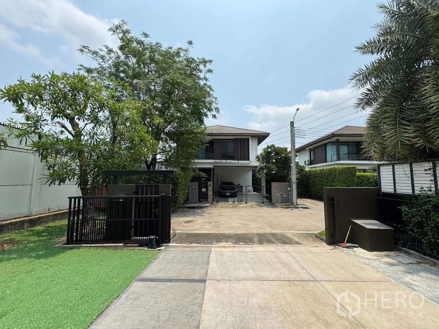 Detached House for rent in Prawet, Bangkok - View from the front gate across the long driveway to the two-storey house on a quiet street.