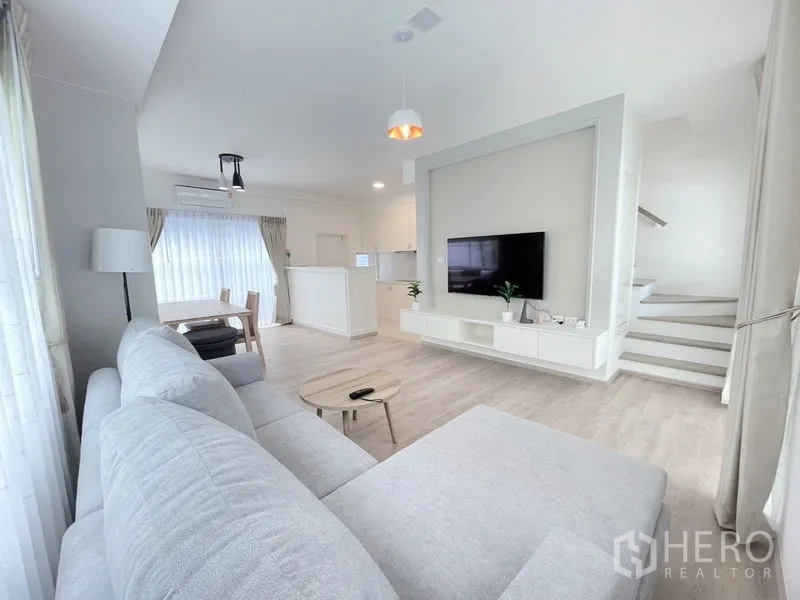 联排别墅 出租在Prawet, Bangkok - 开放式客厅，墙挂电视与通往二楼的楼梯。