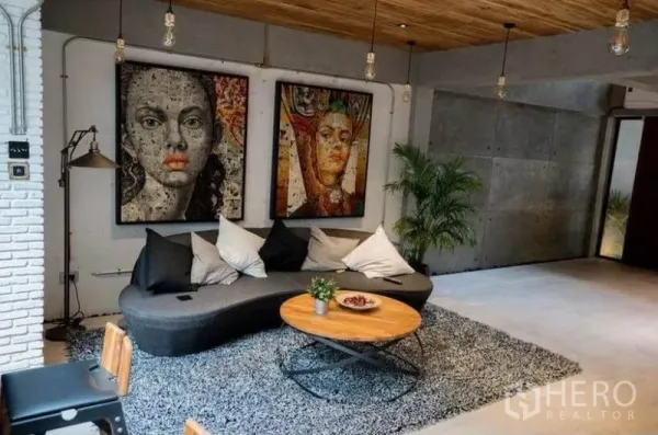 ทาวน์เฮาส์ ให้เช่าในKhlong Toei, Bangkok - มุมนั่งเล่นอบอุ่น โซฟาทรงโค้ง โต๊ะกลาง พรมสัมผัสนุ่ม และภาพศิลป์ขนาดใหญ่