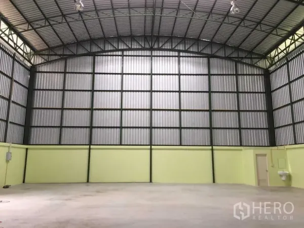 Warehouse for rent in Lat Krabang, Bangkok - Spacious warehouse interior with a high arched steel roof, concrete floor, utility sink and a small service room.