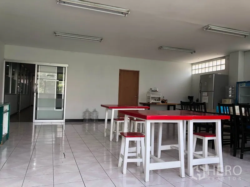 Warehouse for rent in Chatuchak, Bangkok - Staff pantry and dining area with red-top tables, stools, fridge and water dispenser.