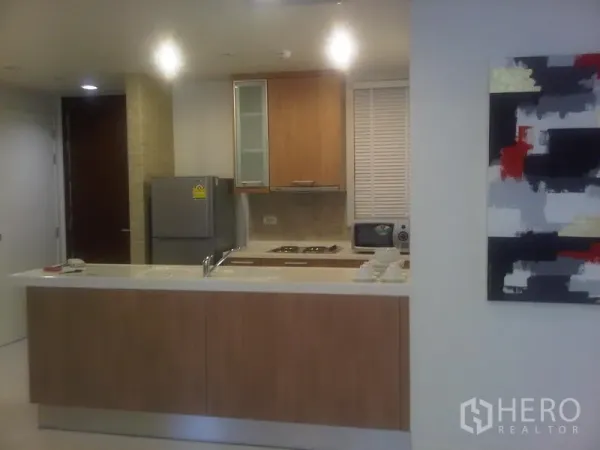 公寓 出售在Ratchathewi, Bangkok - 开放式厨房，吧台、冰箱、炉灶与上柜，灯光柔和。