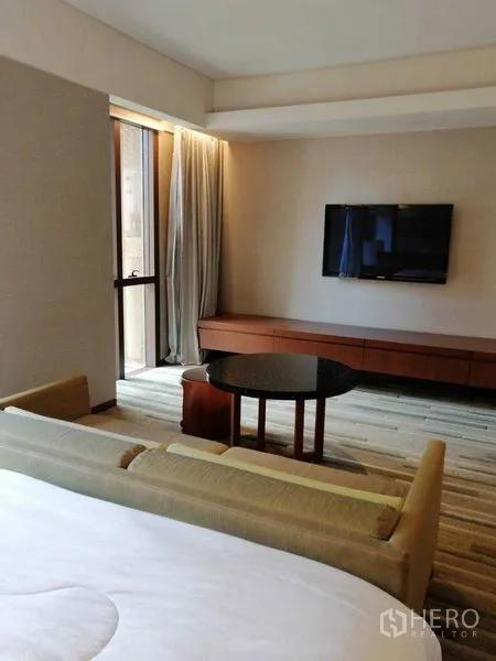 คอนโด ให้เช่าในPathum Wan, Bangkok - มุมนั่งเล่นทีวีติดผนัง ประตูระเบียงและผ้าม่านข้างเตียง