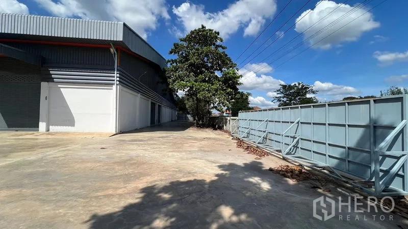 Warehouse for rent in Thanyaburi, Pathum Thani - Private driveway leading to a large metal sliding gate beside the warehouse.