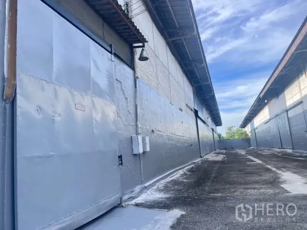 工厂 出租在Bang Pakong, Chachoengsao - 仓库卷帘门、电气箱与外部通行车道特写。