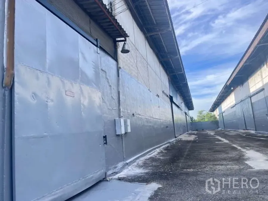 工厂 出租在Bang Pakong, Chachoengsao - 仓库卷帘门、电气箱与外部通行车道特写。