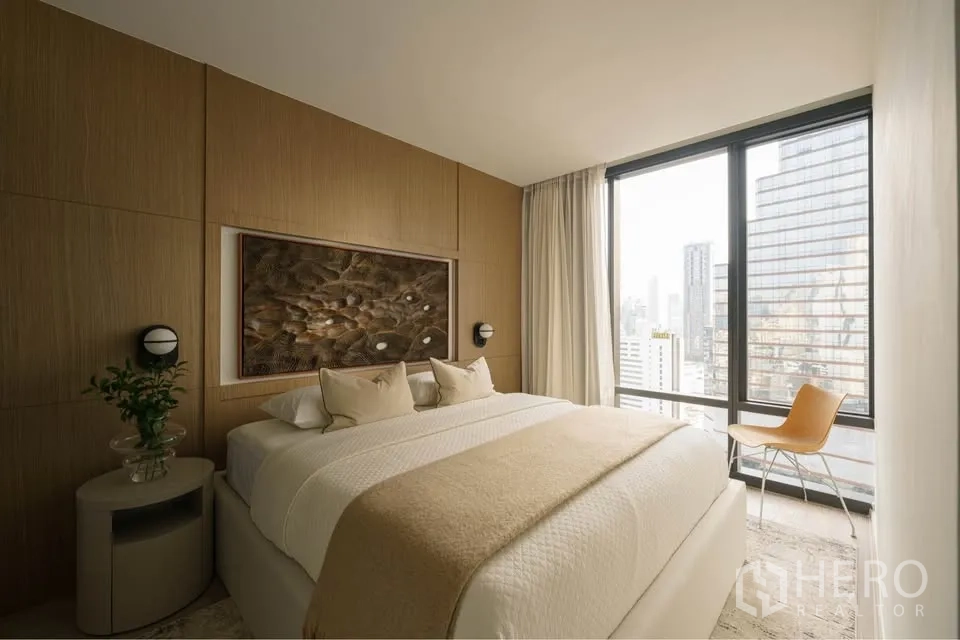 Condominium for rent in Bang Rak, Bangkok - Bedroom with large bed, wood accent wall, and tall windows to the skyline.