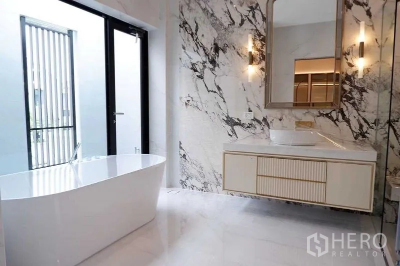 Detached House for sale in Saphan Sung, Bangkok - Luxury bathroom with a freestanding tub, marble feature wall and vanity lighting.