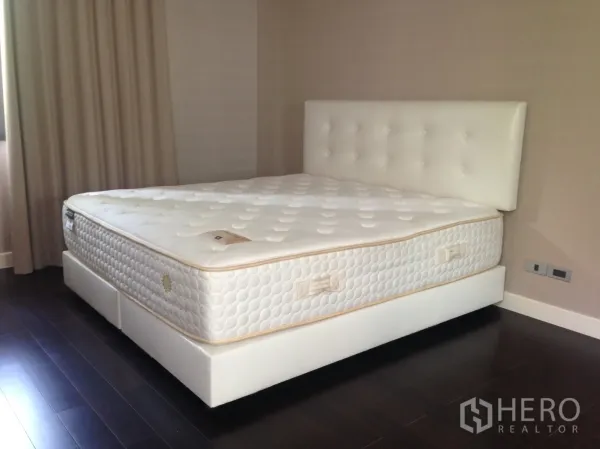 ทาวน์เฮาส์ ให้เช่าในBang Kapi, Bangkok - ห้องนอนพร้อมเตียงใหญ่บุหนังสีขาว พื้นไม้เข้ม และผนังโทนอบอุ่น