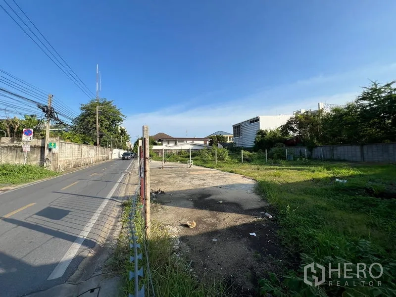 ที่ดิน ขายในBang Na, Bangkok - ถนนย่านที่พักอาศัยพร้อมสายไฟ นำไปสู่แปลงที่ดินว่างมีกำแพงล้อม