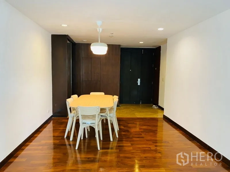 Condominium for rent in Watthana, Bangkok - Dining area with six-seat table, pendant light, and wood floors near the entryway.