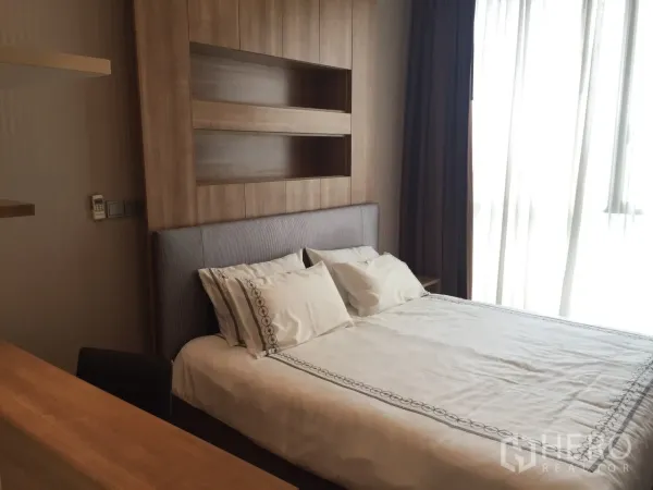 Condominium for rent or sale in Watthana, Bangkok - Cozy bedroom with wood headboard, soft lighting and large window.