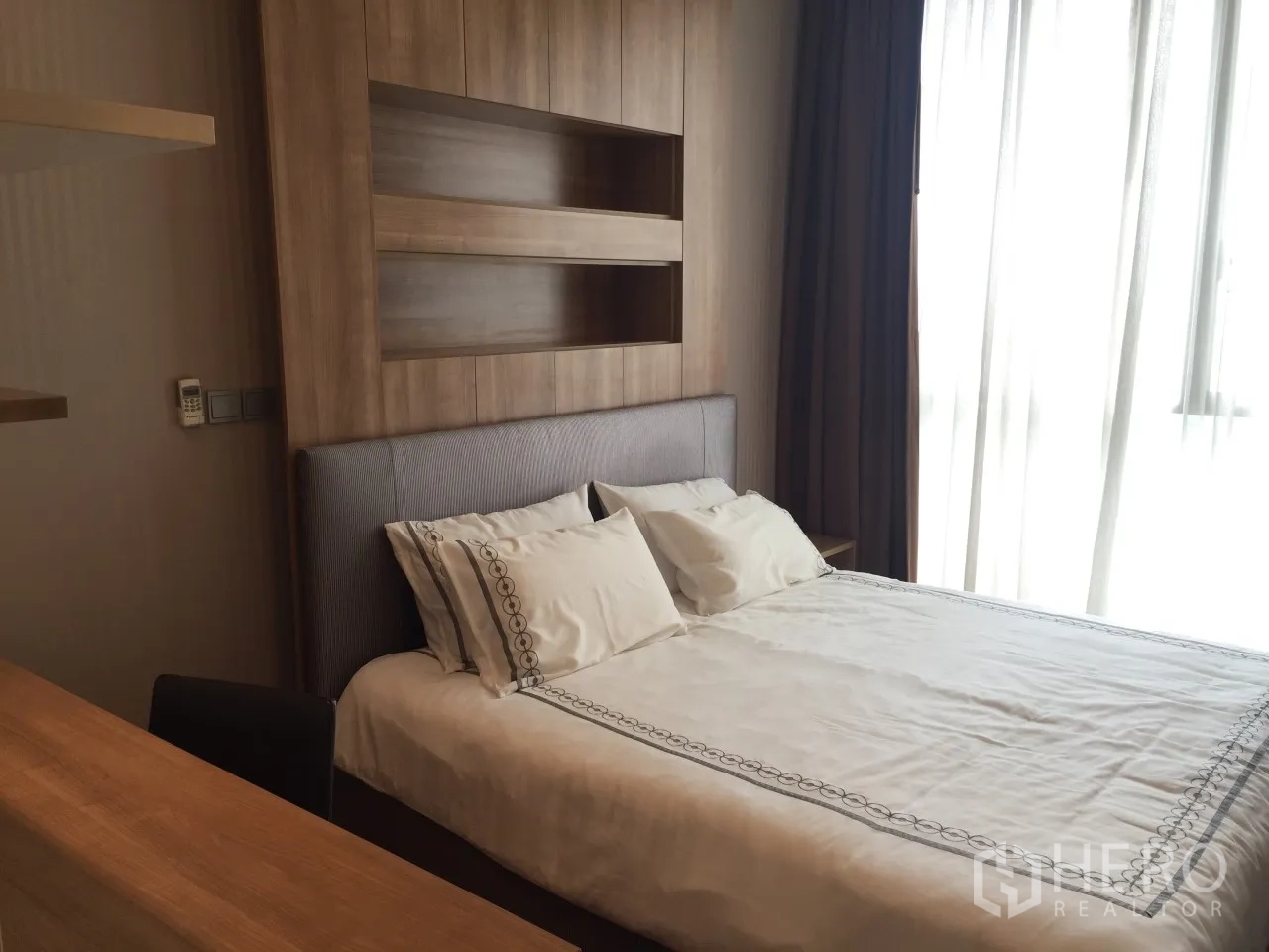 Condominium for rent or sale in Watthana, Bangkok - Cozy bedroom with wood headboard, soft lighting and large window.