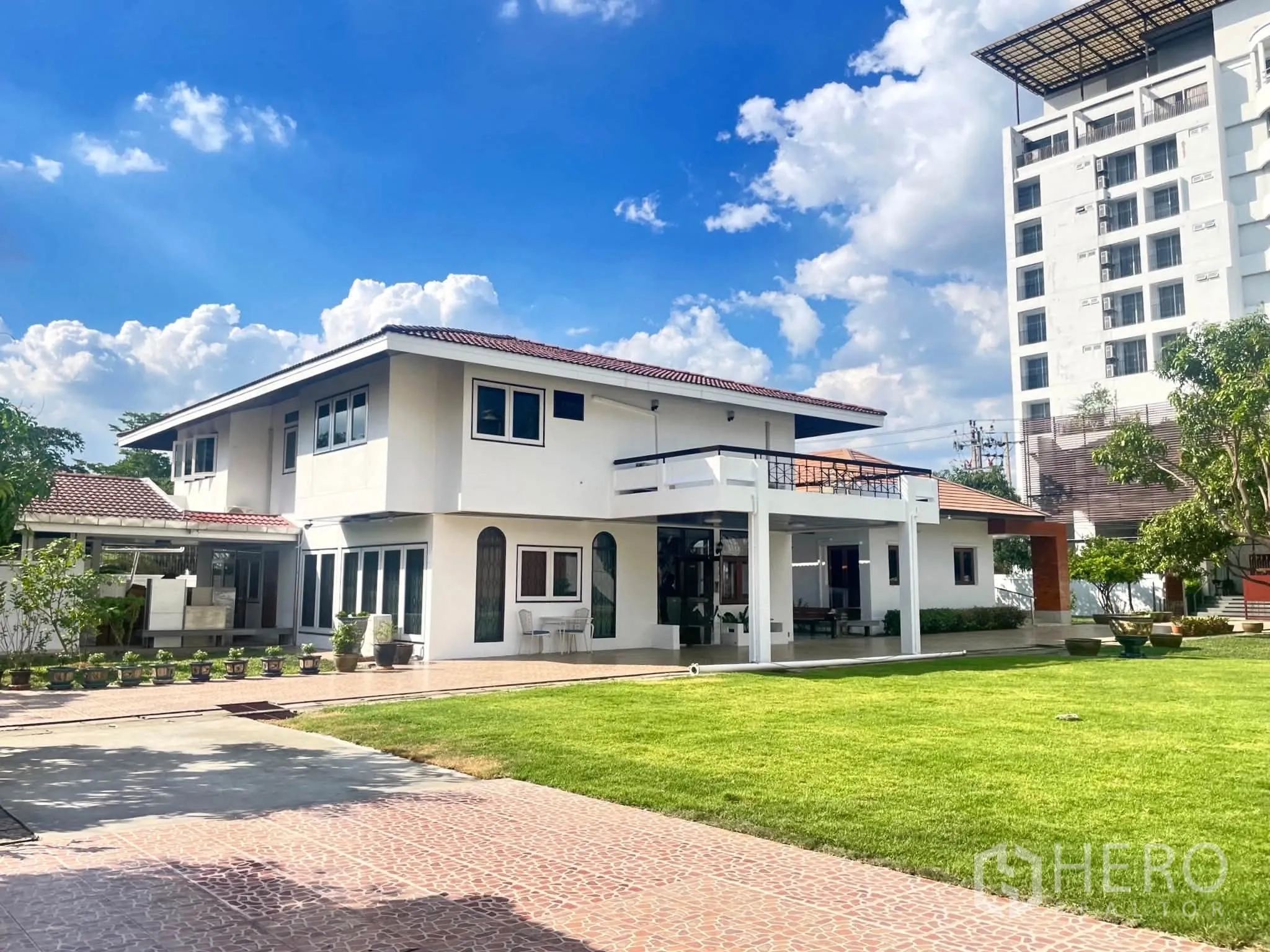 Home Office for rent in Bang Na, Bangkok - Angle view of the main building with terrace and landscaped yard under blue sky.