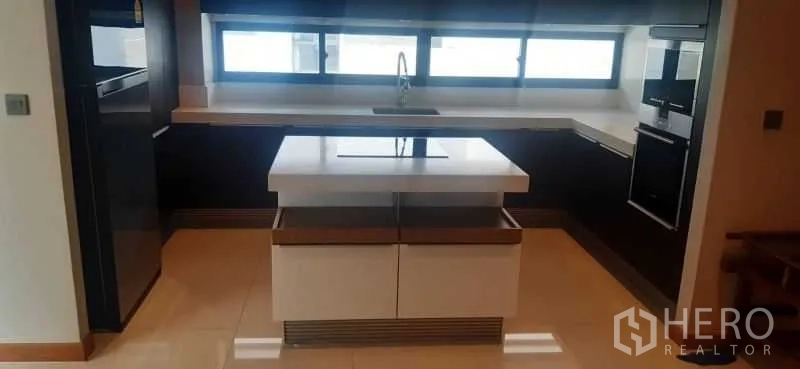 Detached House for rent or sale in Huai Khwang, Bangkok - U-shaped kitchen with island, sink under a long window and ample storage.