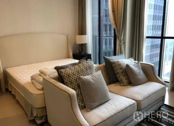 คอนโด ให้เช่าในPathum Wan, Bangkok - ห้องนอนติดหน้าต่างบานเต็มผนัง วิวเมือง เตียงคู่และโซฟา 2 ที่นั่งพร้อมหมอนอิง