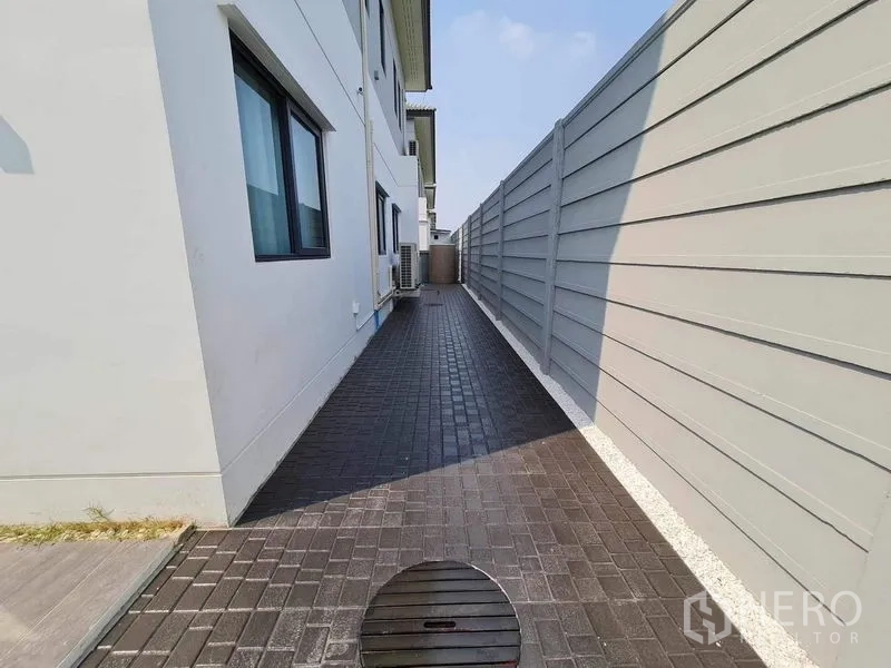 Detached House for rent or sale in Bang Phli, Samut Prakan - Paved side walkway beside the house with privacy wall and service area.