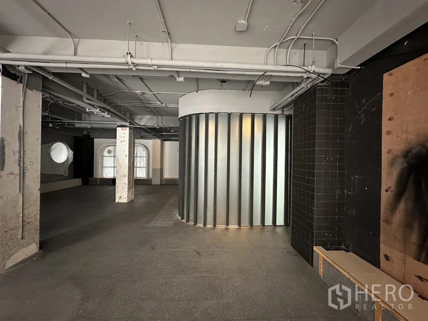 Retail Space for rent in Watthana, Bangkok - Industrial space featuring a ribbed curved metal wall, tiled pillar, and grey flooring.